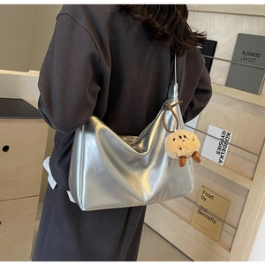 Detail van zilveren hobo-tas met ledertextuur en bruine pluche knuffelhanger