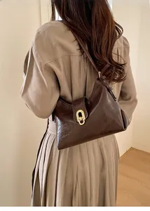 Detail of vintage brown underarm bag showing golden twist lock and glossy leather texture