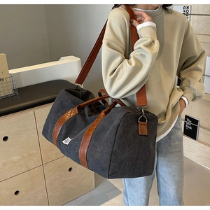Détail d'un grand sac de voyage en toile montrant les poignées en cuir et la bandoulière