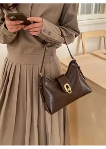 Detail view of dark brown faux leather shoulder bag with vintage gold oval turn lock closure