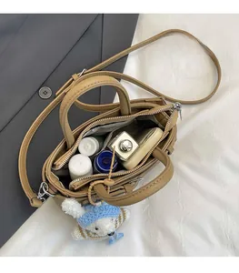 Top view of camel litchi leather bag showing spacious interior compartments and blue bear charm