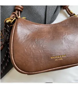 Close-up of brown vintage shoulder bag with golden brand logo and knotted strap detail