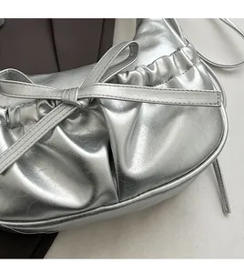Détail du nœud en ruban argenté brillant et de la texture plissée du cuir synthétique