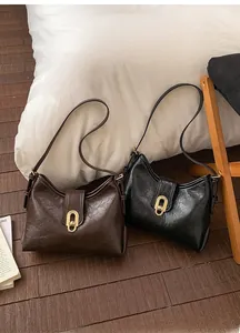 Detail of vintage oil-wax leather shoulder bags in black and brown with gold metal locks