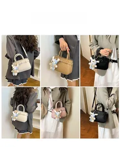 Detail view of lychee leather bucket bag showing crossbody strap and cute rabbit pendant