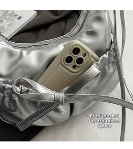 Détail du sac argenté à nœud montrant la poche avant pour smartphone et l'aspect plissé