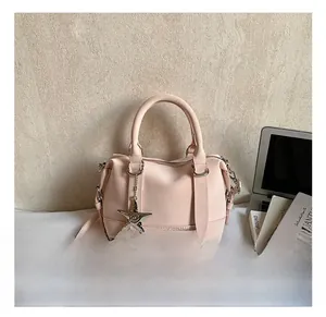 Détail du sac Boston rose clair avec pendentif étoile et texture en cuir mat