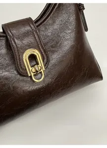 Detail of vintage dark brown faux leather bag with shiny golden oval metal clasp