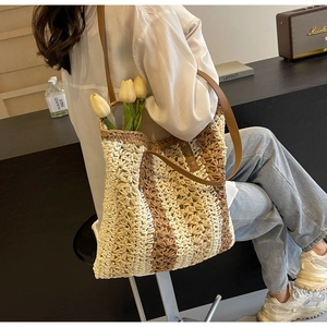 Detail der handgeflochtenen Strohtasche mit braunem Lederriemen und Kontrastnähten