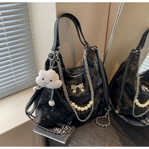 Details der schwarzen Metallic-Tasche mit Silberschleife, Perlenkette und Anhänger