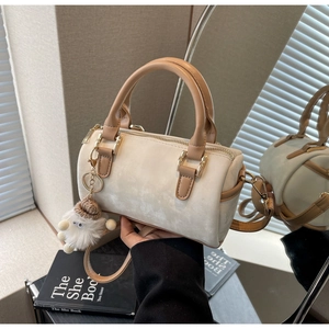 Détail du sac Boston beige avec poignées marron et pendentif agneau en peluche