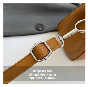 Detail of adjustable leather shoulder strap with silver metal buckle on brown crossbody bag