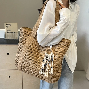 Grand sac cabas en paille tissé à la main avec gland décoratif porté par un mannequin