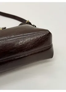 Detailed view of the dark brown leather bag bottom featuring smooth stitching and grain texture