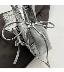 Détail d'un sac à main plissé argenté avec cordon de serrage sur fond de costume gris