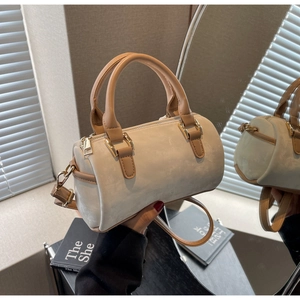 Détail du mini sac Boston avec texture en daim beige, poignées camel et fermeture éclair dorée