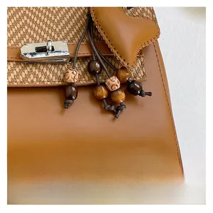 Detail of retro leather and woven bag featuring silver twist lock and heart pendant