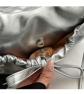 Détail du sac à nœud argenté montrant le fermoir magnétique et les plis du bord