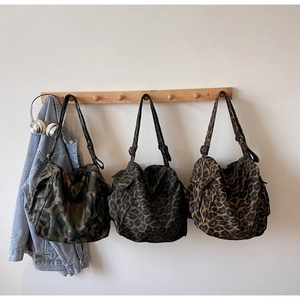 Three large tote bags with camo and leopard prints shown hanging in a casual setting