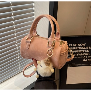Détail du sac Boston en daim rose avec fermeture éclair dorée et pendentif mouton en peluche