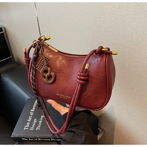 Detail of burgundy leather shoulder bag with decorative abacus and knot strap
