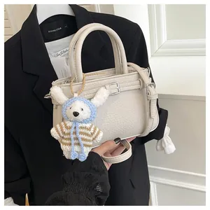 Detail of beige lychee grain leather handbag with a cute plush rabbit charm accessory