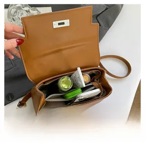 Detail view of the spacious interior of this brown leather crossbody bag with daily essentials