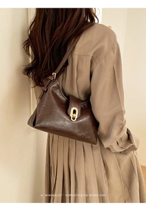 Detail of vintage brown textured leather underarm bag with gold oval clasp and strap buckles