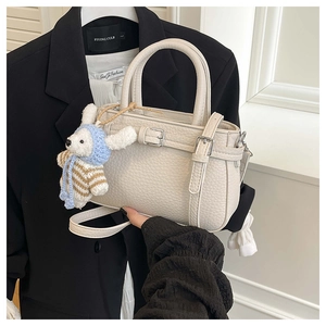 Detail of off-white lychee pattern leather bucket bag with cute bunny charm and metal buckles