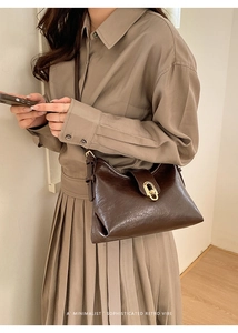 Detail of retro dark brown leather shoulder bag featuring a polished gold twist lock