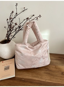 Close-up of pink satin tote bag with traditional Chinese embroidery on a wooden table