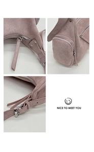 Detail shot of pale pink suede handbag with silver metal zipper and adjustable strap