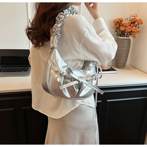 Modèle portant un sac hobo plissé argenté avec nœud décoratif et bandoulière à volants