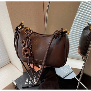 Detail of dark brown glossy underarm bag with stylish knot strap and gold ring hardware