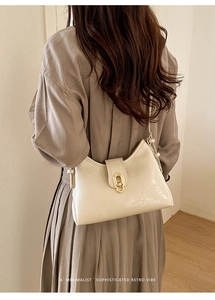 Detail shot of cream-colored shoulder bag with gold oval clasp on minimalist retro design