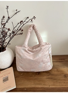 Detailed shot of pink satin tote bag with traditional embroidery and tassel on a table