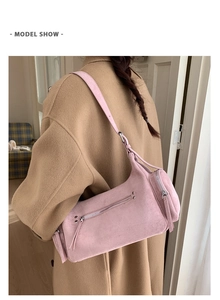 Detail of pink faux suede cylinder shoulder bag with silver zipper on camel coat