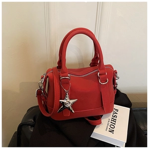 Détail du sac polochon en cuir rouge avec pendentif étoile et poignée ronde