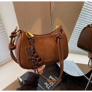 Detail of vintage brown leather underarm bag with knot strap and golden abacus charm