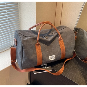 Détail du sac de voyage en toile avec poignées en simili cuir brun et bandoulière amovible