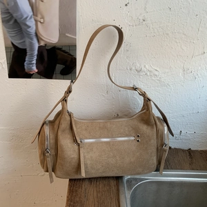 Detailed close-up of brown suede shoulder bag showing silver zippers and rich texture