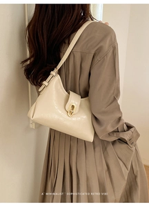 Detail of cream retro underarm bag featuring elegant gold clasp and smooth vegan leather