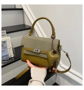 Detail of olive green handbag with houndstooth flap and heart charm on stairs
