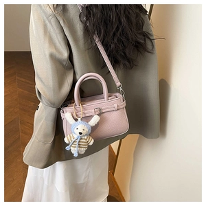 Detail of pink pebbled leather bucket bag featuring a cute white rabbit plush charm