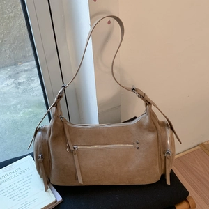 Detail of brown suede Boston bag featuring multiple zippers and adjustable long strap