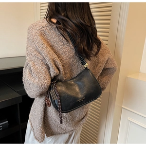 Detail of black vintage moon bag featuring knotted strap, golden hardware and side tassels