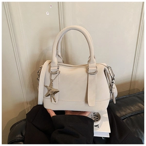 Détail du sac polochon crème avec pendentif étoile et bandoulière amovible élégante