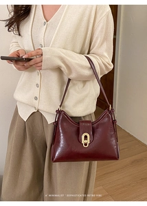 Detail showing high-gloss wine red leather texture and elegant gold oval metal clasp