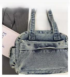 Detailed close-up of a blue washed denim handbag with functional zipper pockets and reinforced stitching