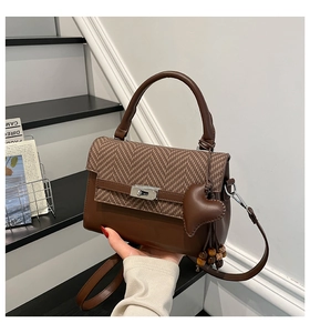 Detailed view of brown crossbody bag with houndstooth flap and silver turn-lock closure